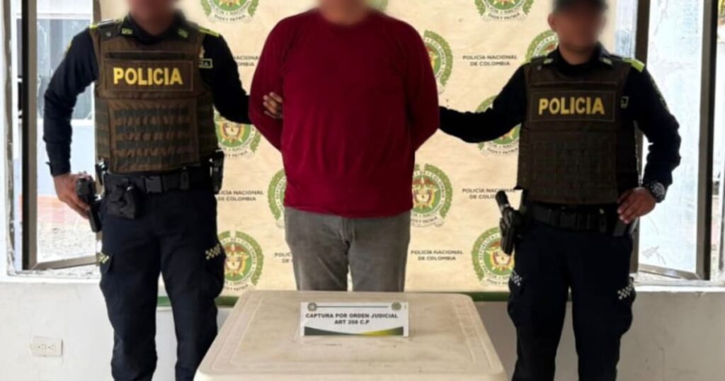 Imagen de un agente de policía llevando a un hombre esposado, por abuso a una menor