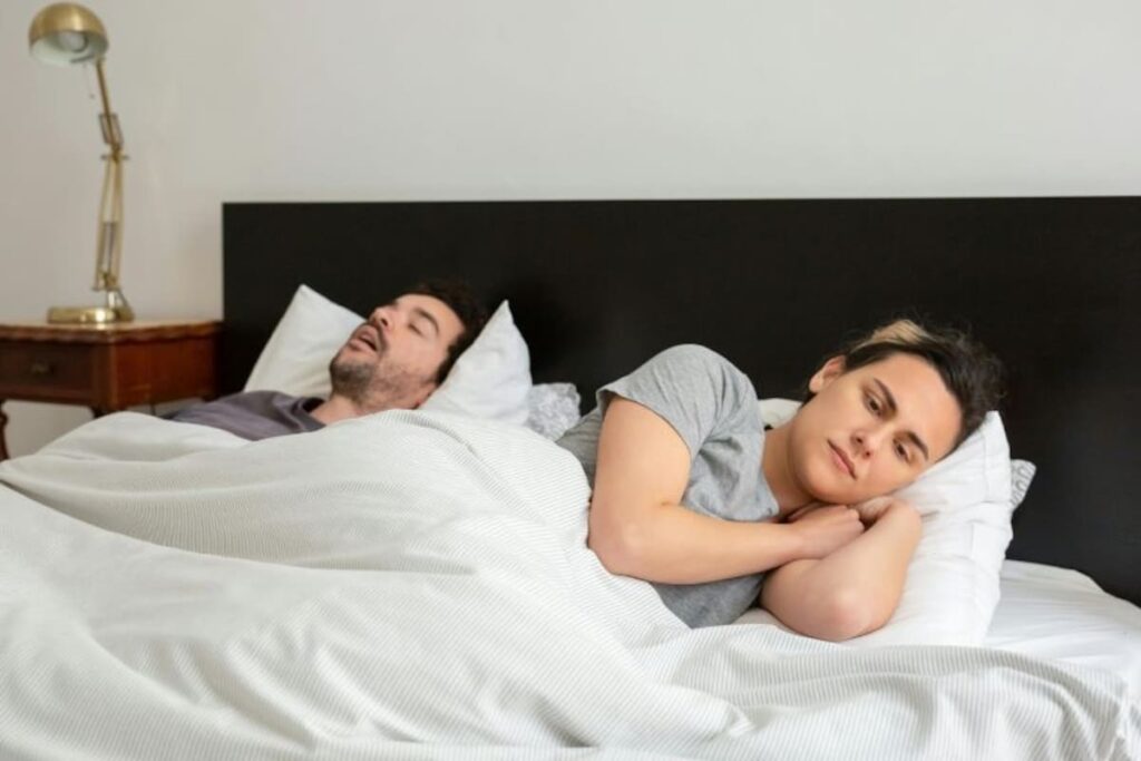 Pareja en una cama, con una expresión de sueño interrumpido