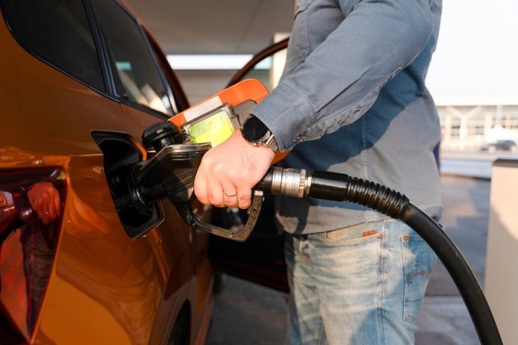 Una persona llenando el tanque de gasolina de su vehículo en una estación de servicio.