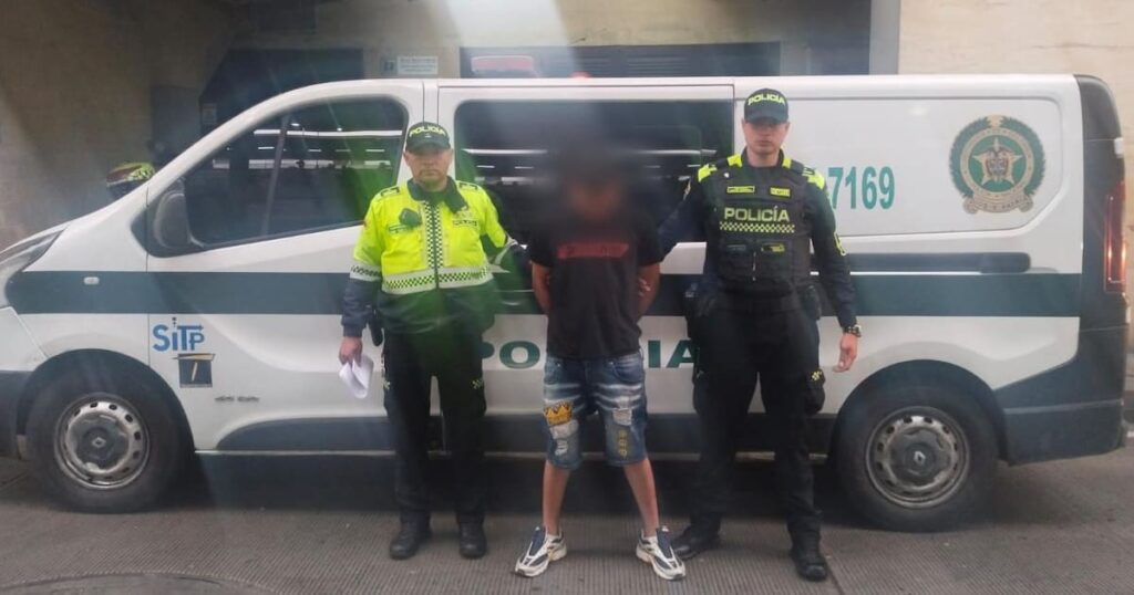 Imagen de un agente de policía realizando un arresto en una estación de Transmilenio