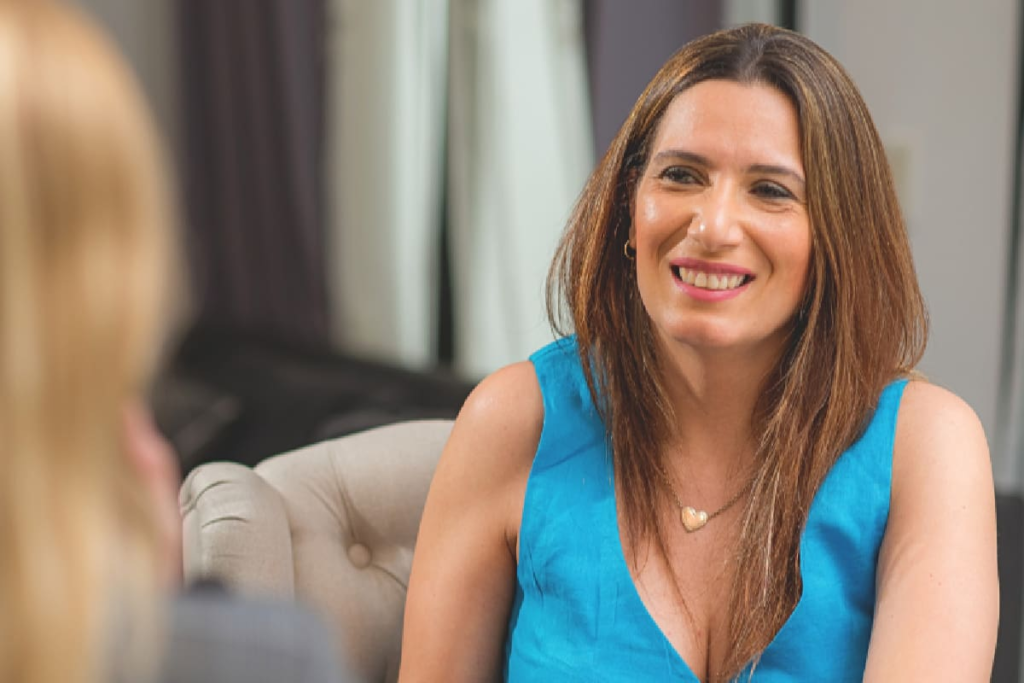 Mujer sonriendo mientras camina hacia adelante con un paisaje de montañas al fondo, simbolizando superación y resiliencia