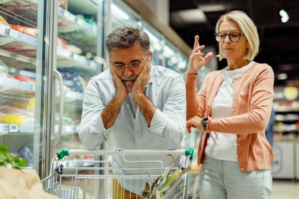 Una familia estadounidense revisando su presupuesto con una expresión de preocupación, con facturas y estados de cuenta sobre la mesa
