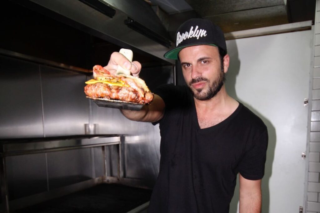 Imagen de una hamburguesa clásica con queso, tomate, lechuga y mayonesa sobre una parrilla.