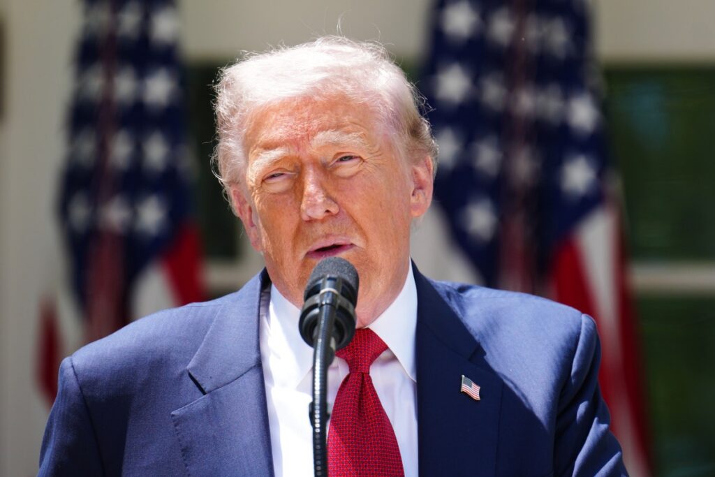 Donald Trump hablando en una rueda de prensa con banderas de Estados Unidos, Rusia y Ucrania de fondo