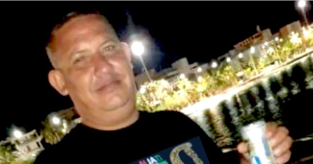 Imagen de una gallera con gente en el fondo y un hombre herido en el suelo