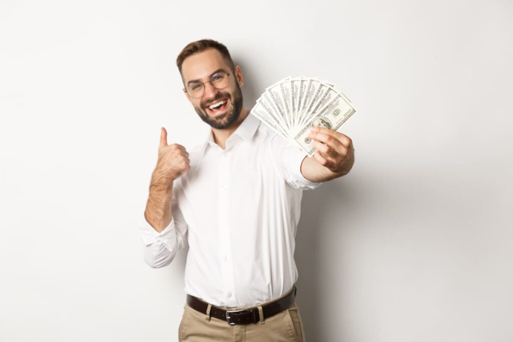 Una persona sostiene un fajo de billetes de manera segura, sonriendo.