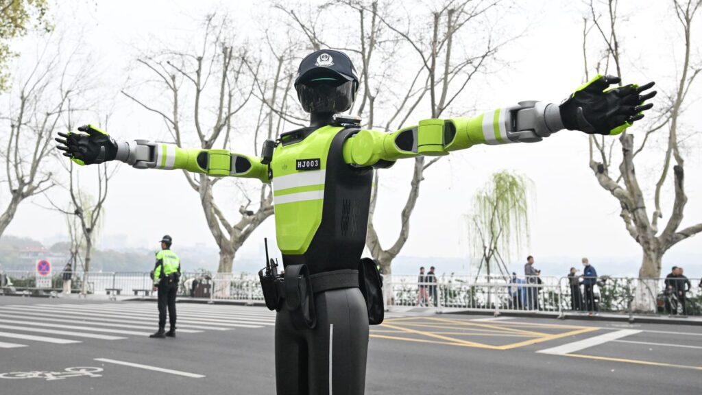 Una imagen de una mano de robot realizando tareas de oficina, junto a una persona trabajando en una computadora