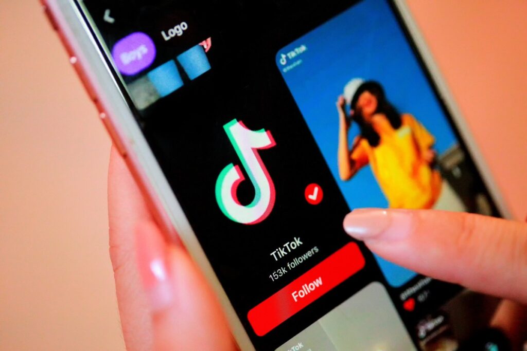 Persona usando smartphone con app TikTok y billetes de dólar en pantalla