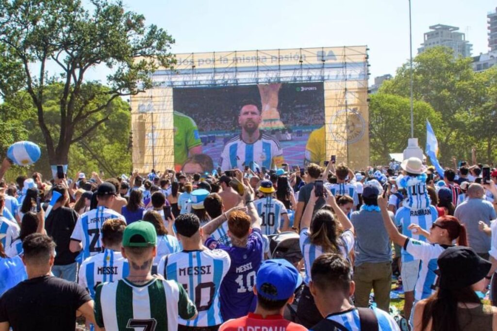 Una pantalla gigante en un festival de fútbol al aire libre con gente disfrutando de un partido
