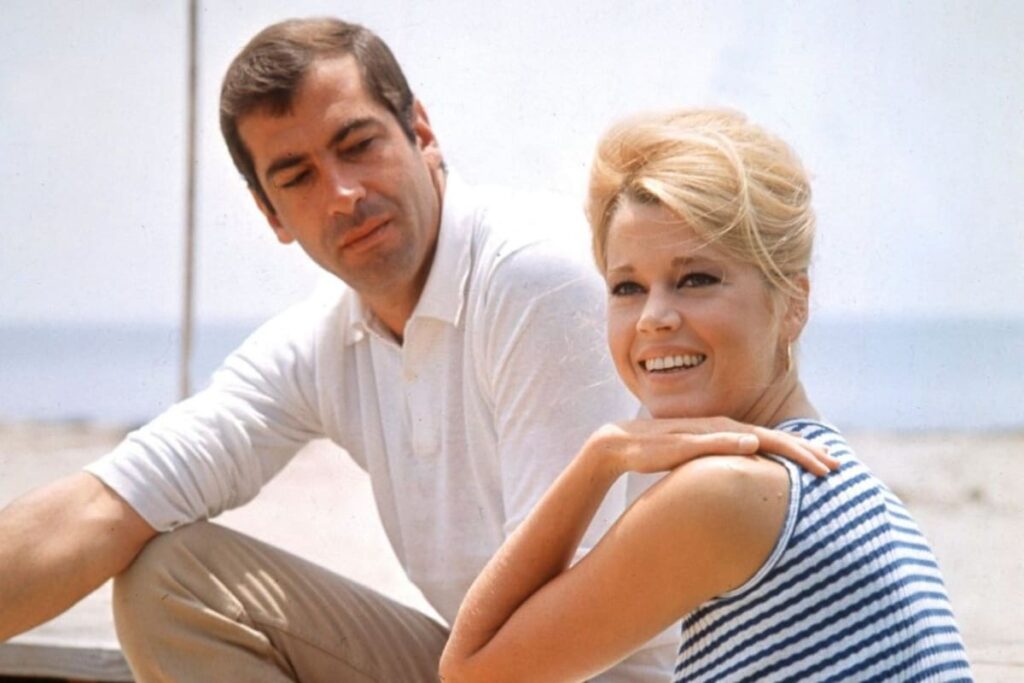 Roger Vadim posando con retratos de Brigitte Bardot, Catherine Deneuve y Jane Fonda