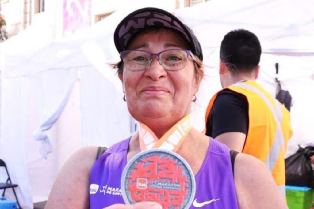 Ely con camiseta morada número 7613 cruzando la meta de la maratón de Santiago